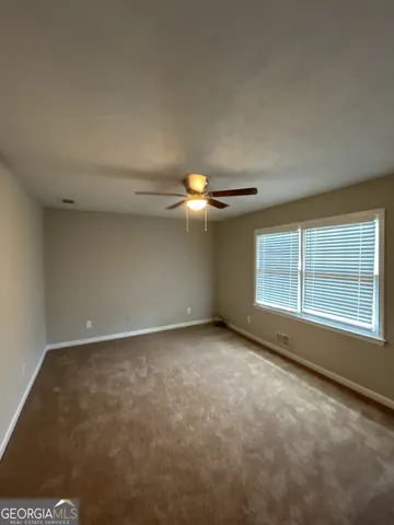 an empty room with a ceiling fan and carpet