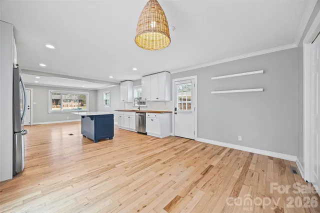 a large white kitchen with kitchen island a sink wooden floor and a refrigerator
