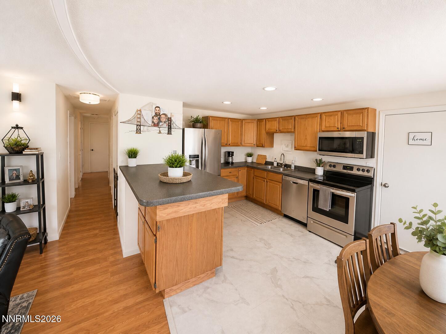 9350 Gremlin Way Reno, NV 89506 - Photo 3 of 7 a kitchen with stainless steel appliances granite countertop a stove top oven a sink dishwasher a dining table and chairs with wooden floor