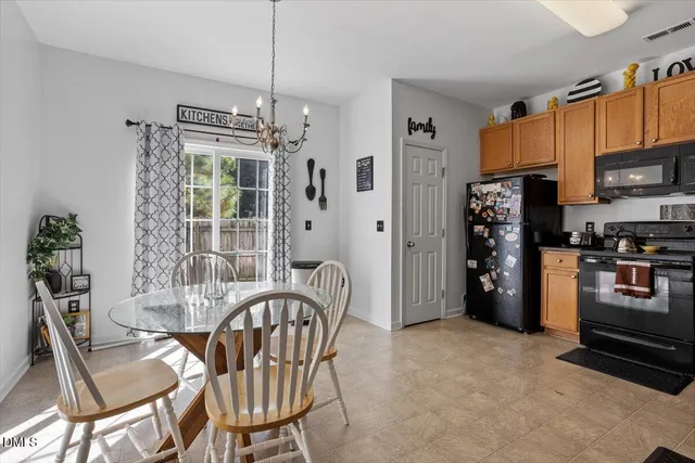 a kitchen with stainless steel appliances a refrigerator a stove a dining table and chairs