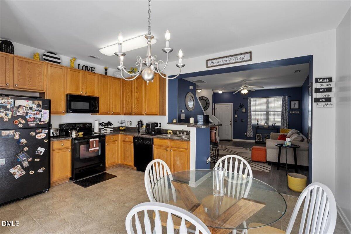 1409 Oxleymare Drive Raleigh, NC 27610 - Photo 19 of 28 a kitchen with stainless steel appliances granite countertop a stove a refrigerator a kitchen island a dining table and chairs with wooden floor