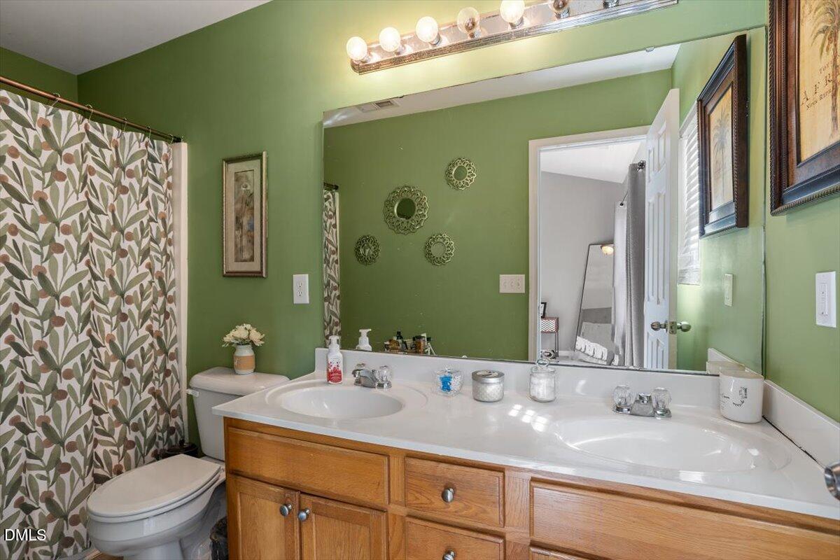 1409 Oxleymare Drive Raleigh, NC 27610 - Photo 24 of 28 a bathroom with a granite countertop sink mirror vanity and toilet