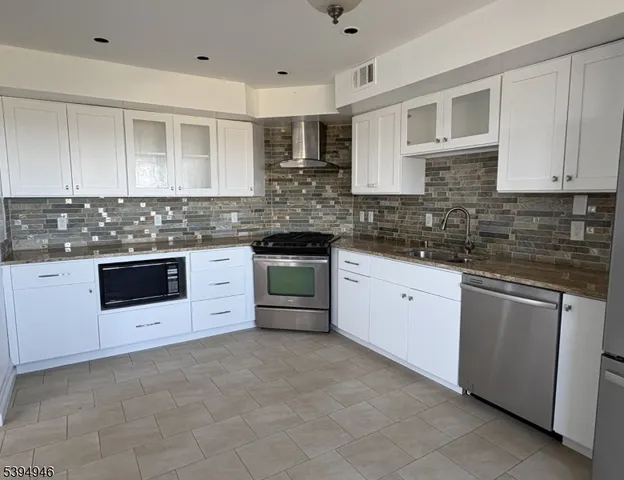 a kitchen with stainless steel appliances granite countertop a stove sink and cabinets