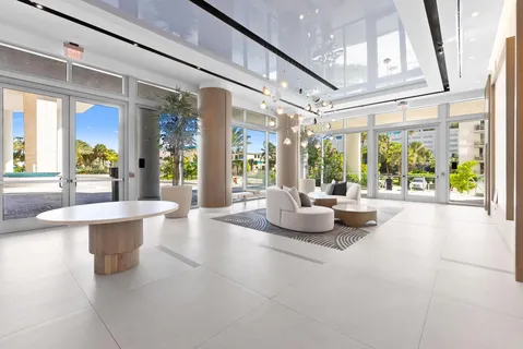 a living room with furniture large windows a rug and a chandelier