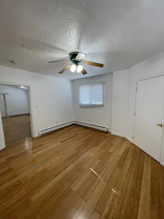 an empty room with wooden floor chandelier fan and windows