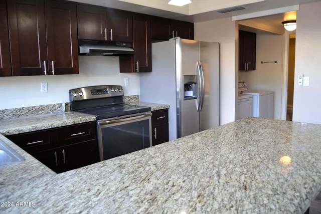 a kitchen with stainless steel appliances granite countertop a refrigerator a stove a sink and a granite counter tops