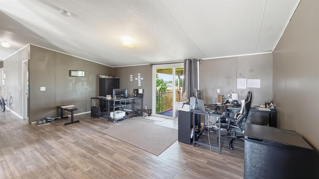 185 Private Road 4437 Rhome, TX 76078 - Photo 6 of 28 Spacious room featuring wood-finish flooring, a sliding glass door providing exterior access, and a ceiling-mounted light fixture