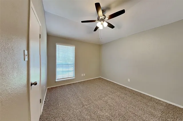 an empty room with a window and a fan