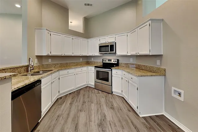 a kitchen with granite countertop a sink a counter top space stainless steel appliances and cabinets