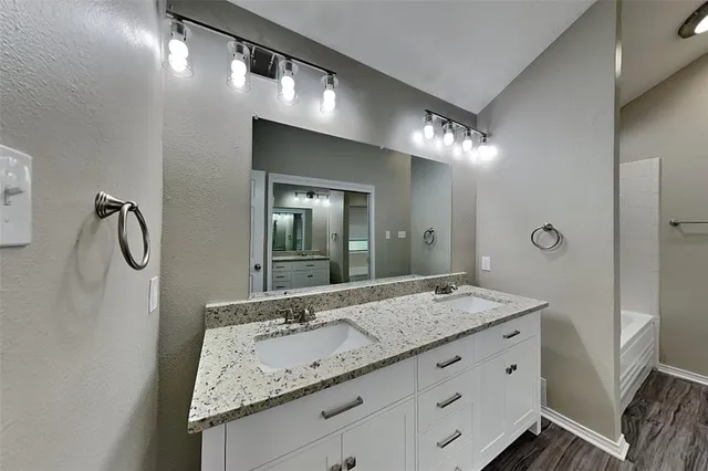 a bathroom with a granite countertop sink and a mirror
