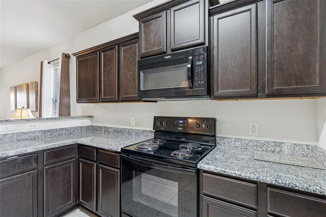 a kitchen with granite countertop cabinets stove and microwave