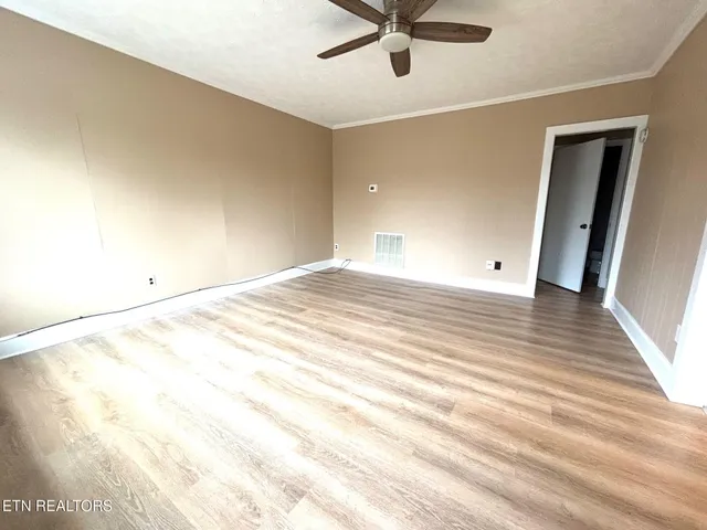 an empty room with wooden floor and windows