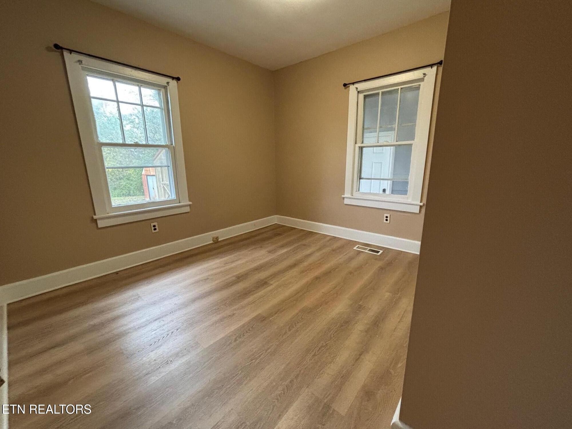 7005 Washington Pike, Unit A Corryton, TN 37721 - Photo 9 of 17 an empty room with wooden floor and windows