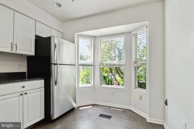 a kitchen with a refrigerator a stove top oven and cabinets