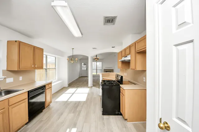 a kitchen with stainless steel appliances granite countertop a refrigerator a stove and a sink with wooden floor