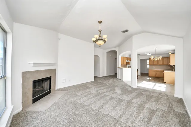 a view of a livingroom with a fireplace a chandelier and windows