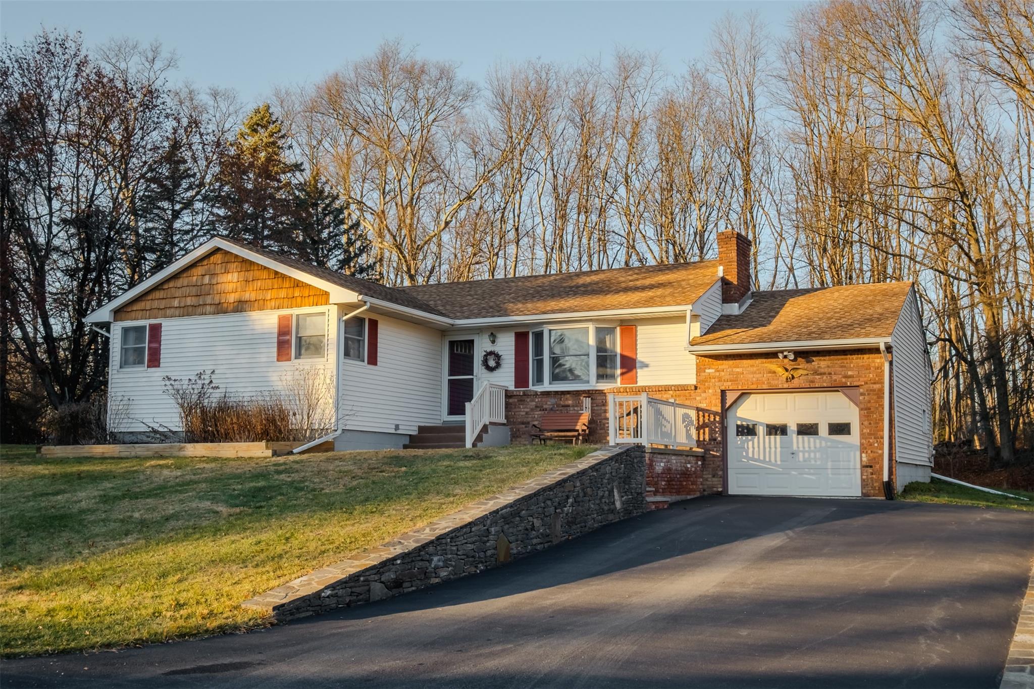 Ranch-style house featuring driveway, a garage, a chimney, a front yard, and brick siding