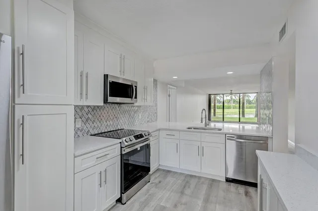 a kitchen with white cabinets and appliances