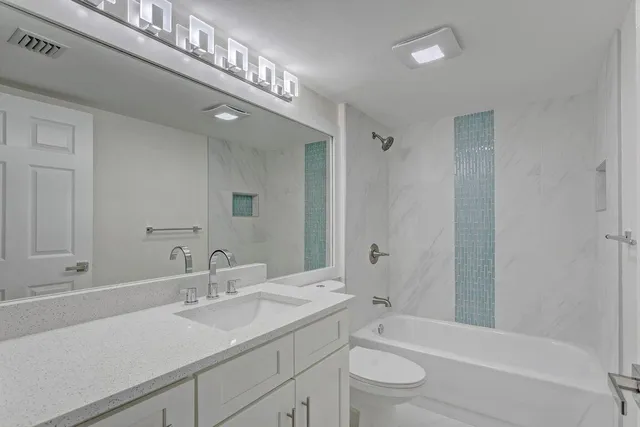 a bathroom with a granite countertop sink a toilet and shower