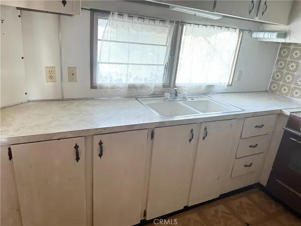 a kitchen with white cabinets and a window