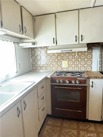 a kitchen with granite countertop a stove sink and cabinets