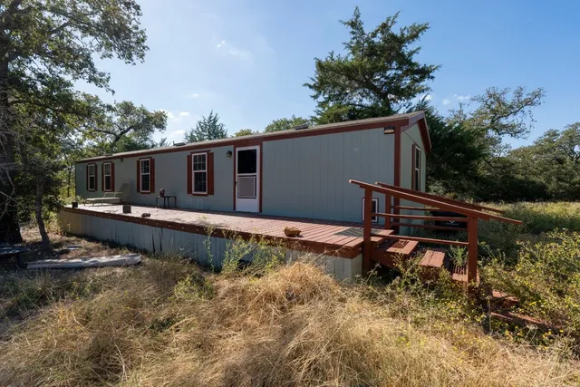 a view of a house with a wooden deck and a trees