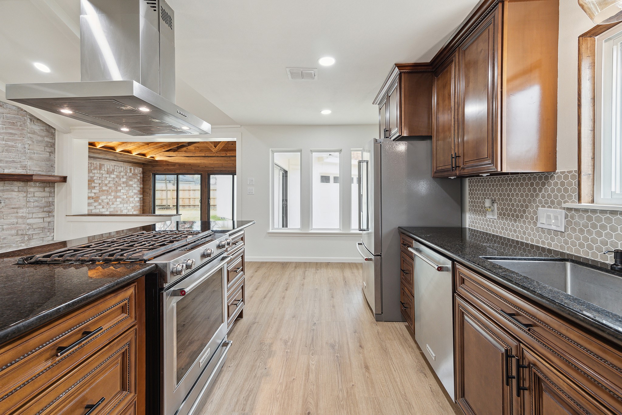9719 Springmont Drive Houston, TX 77080 - Photo 16 of 32 Kitchen is a galley style with a LARGE single basin sink, DW, and fridge opposite cooktop island ... but it is completely open to adjoining rooms so feels so much larger!! Note the modern style tile backsplash!