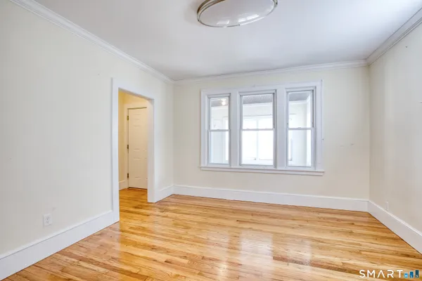 a view of an empty room with wooden floor and a window