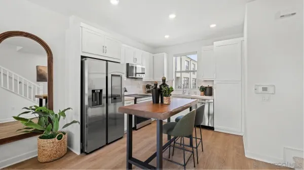 a kitchen with stainless steel appliances a dining table chairs refrigerator and microwave