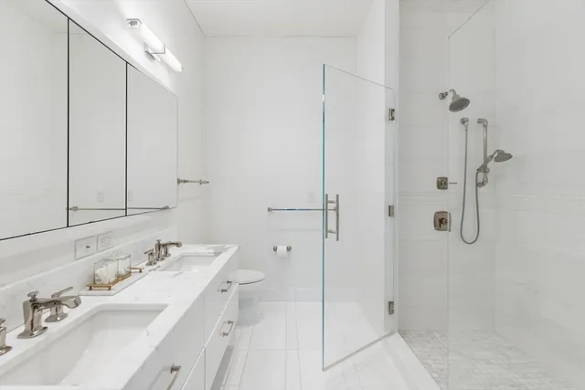 a bathroom with a double vanity sink mirror and shower