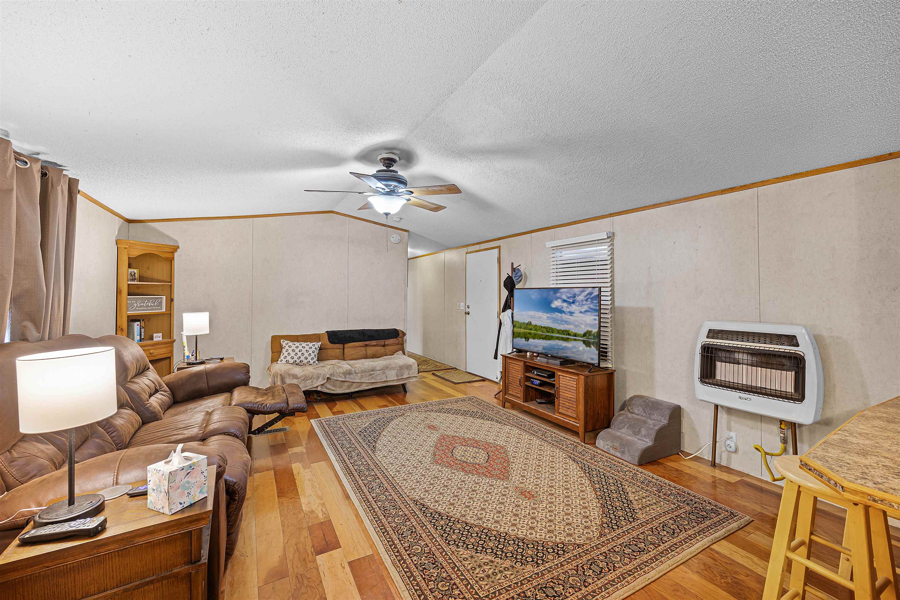 90 Rose Road Crump, TN 38327 - Photo 13 of 28 Living room featuring crown molding, heating unit, light wood-style flooring, a decorative wall, and ceiling fan