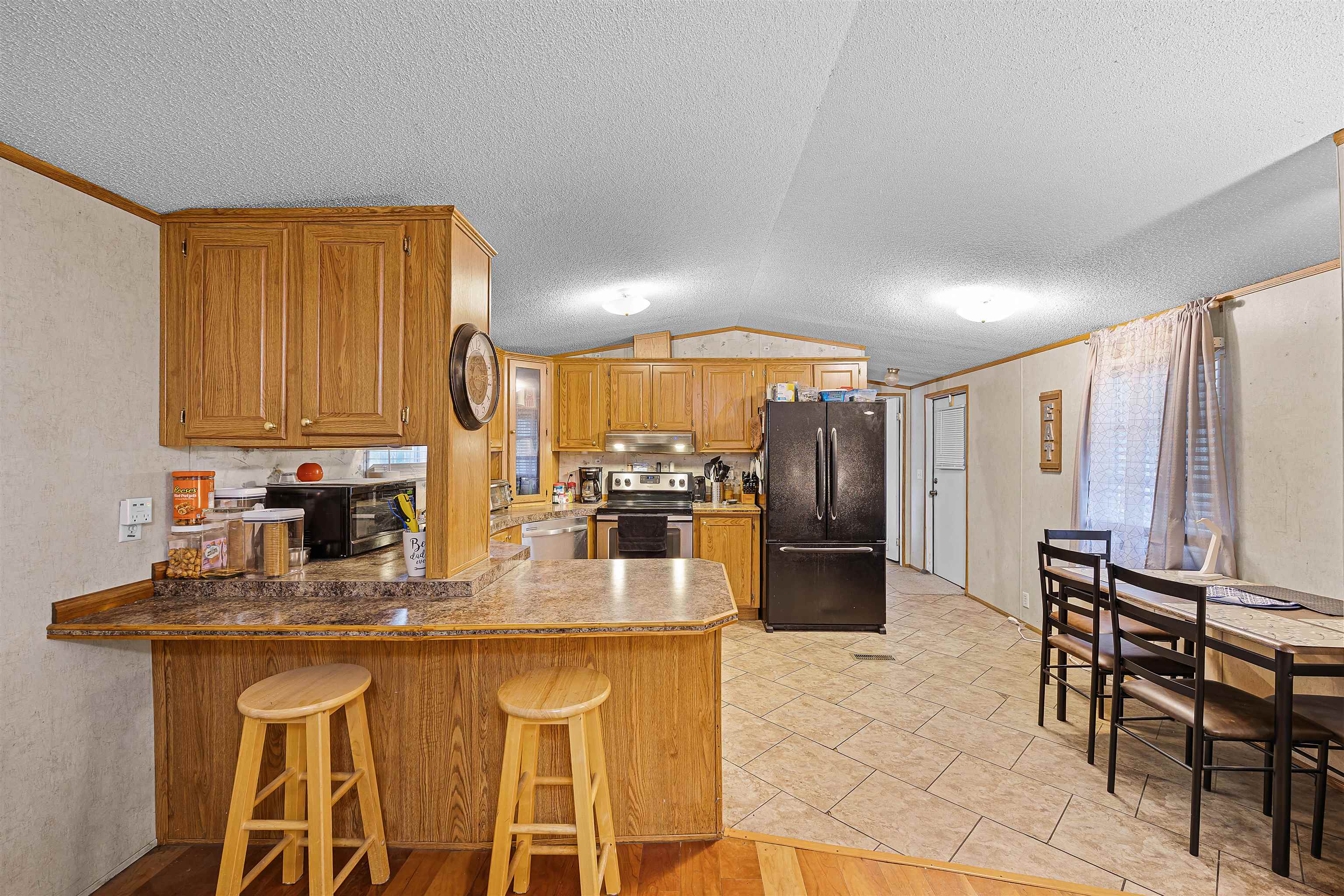 90 Rose Road Crump, TN 38327 - Photo 15 of 28 Kitchen with wood finish cabinetry, a breakfast bar, black appliances, a peninsula, and crown molding