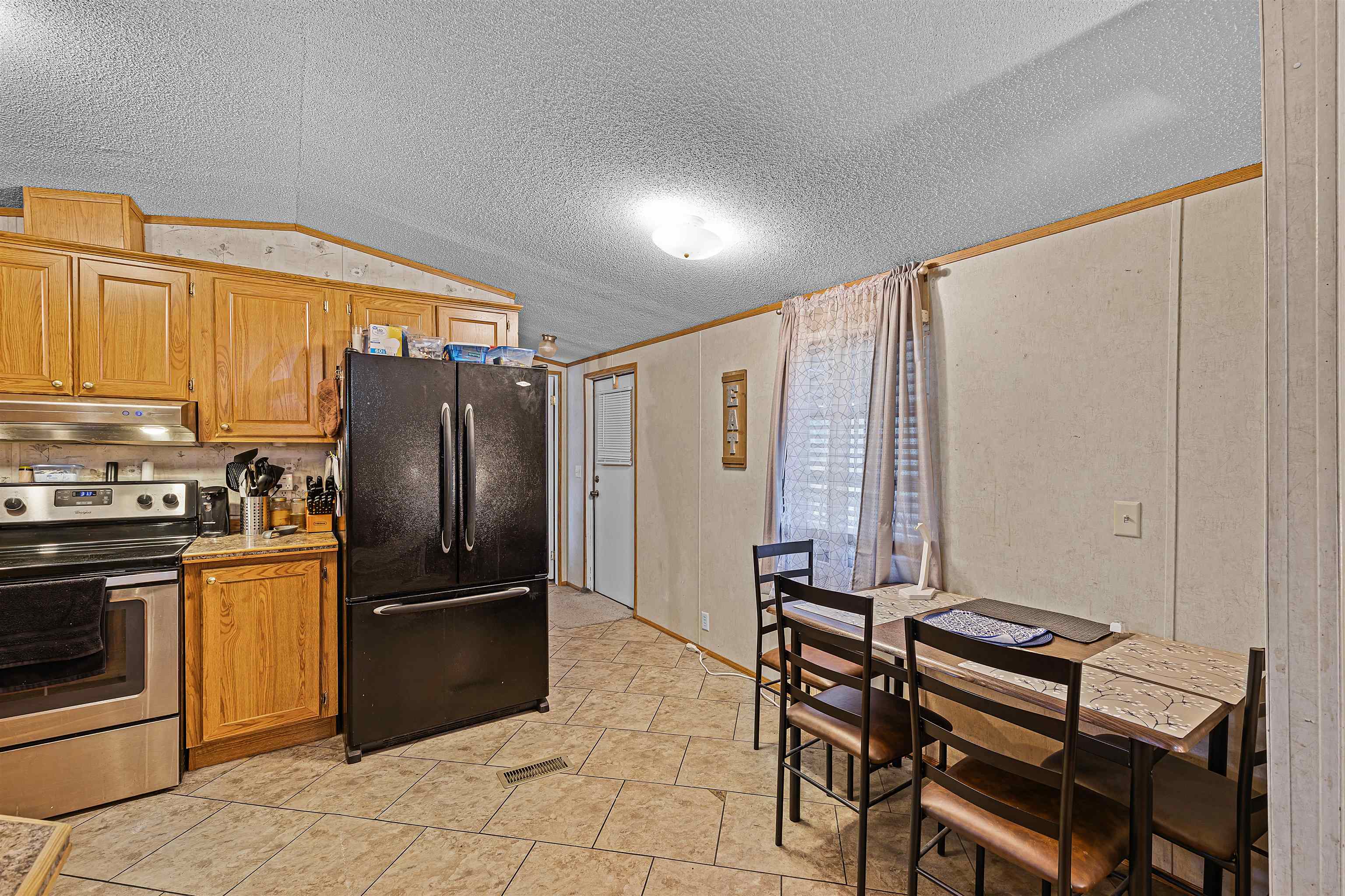 90 Rose Road Crump, TN 38327 - Photo 17 of 28 Kitchen featuring stainless steel range with electric cooktop, wood finish cabinets, freestanding refrigerator, light countertops, and ornamental molding