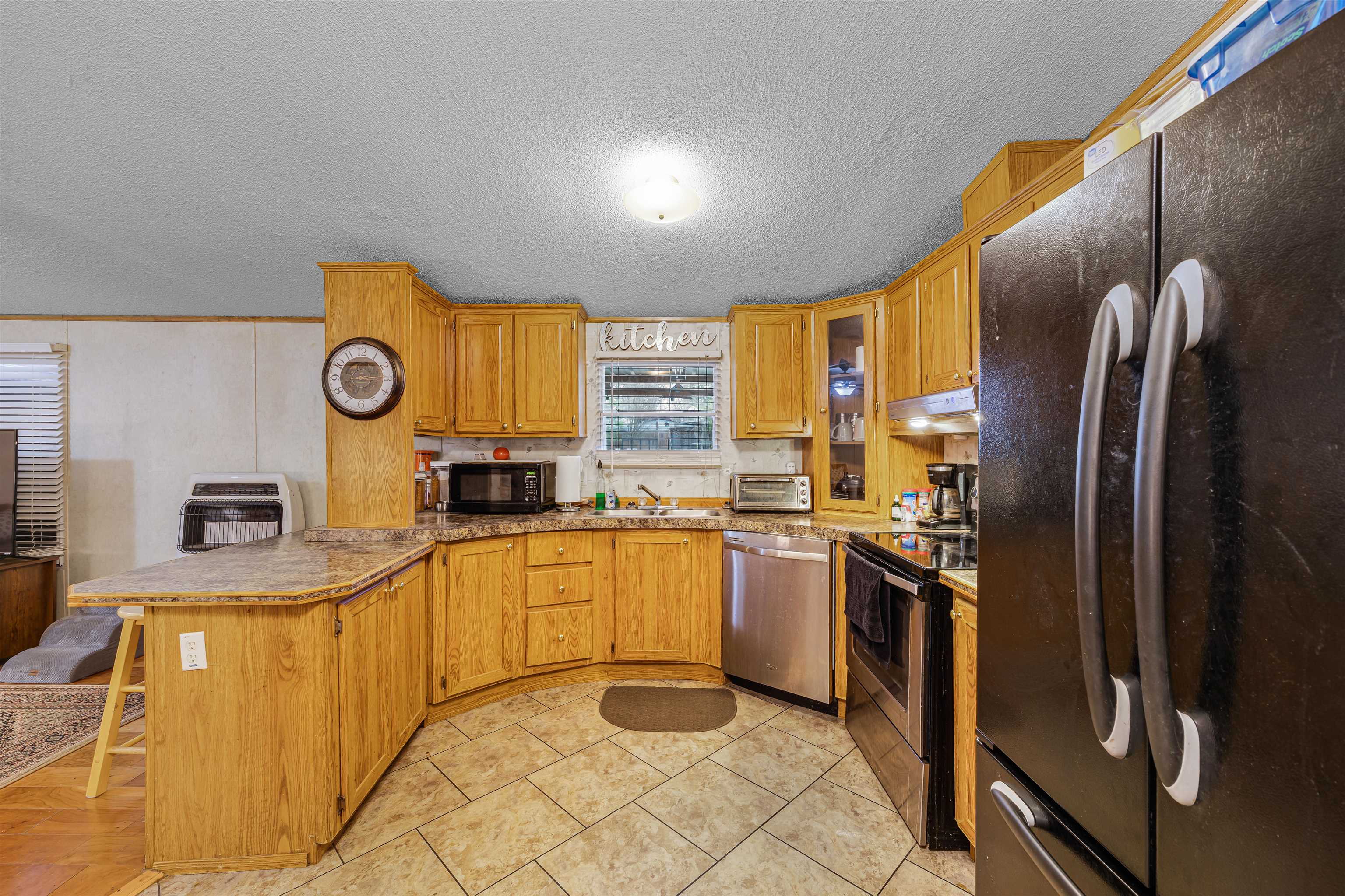 90 Rose Road Crump, TN 38327 - Photo 3 of 28 Kitchen featuring black appliances, a peninsula, a textured ceiling, a breakfast bar area, and heating unit