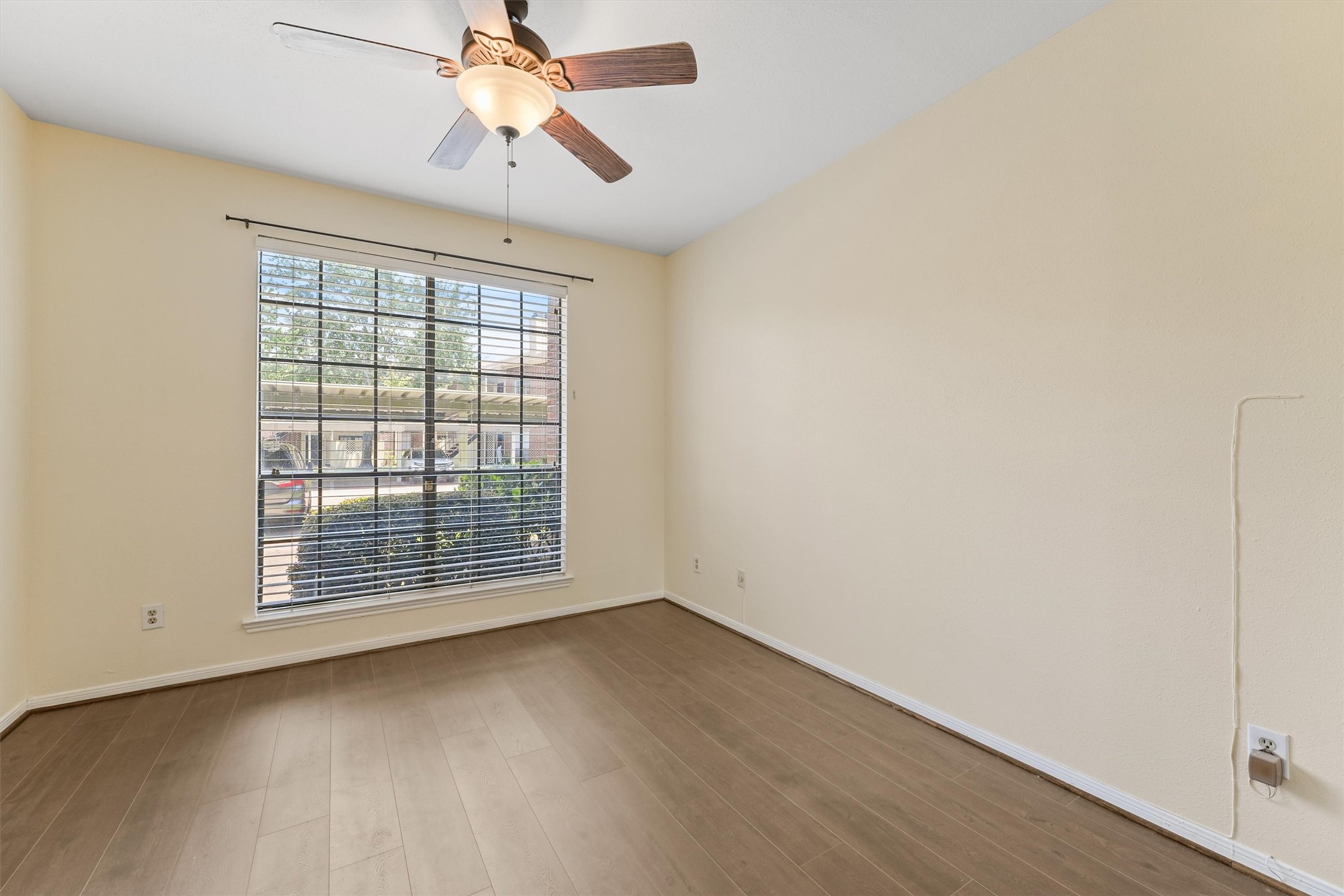 8055 Cambridge Street, Unit 21 Houston, TX 77054 - Photo 12 of 15 an empty room with wooden floor chandelier fan and windows