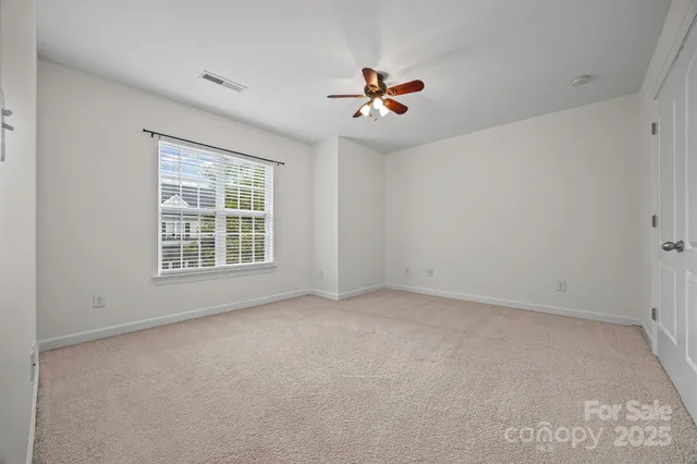 an empty room with windows and ceiling fan