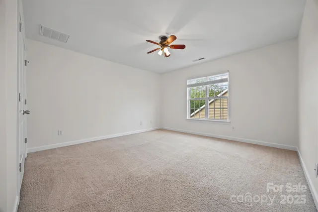 an empty room with windows and ceiling fan