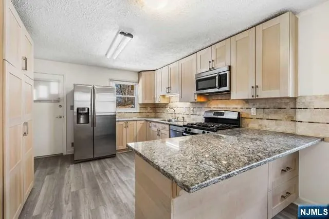 a kitchen with stainless steel appliances granite countertop a refrigerator a stove a sink a microwave and cabinets