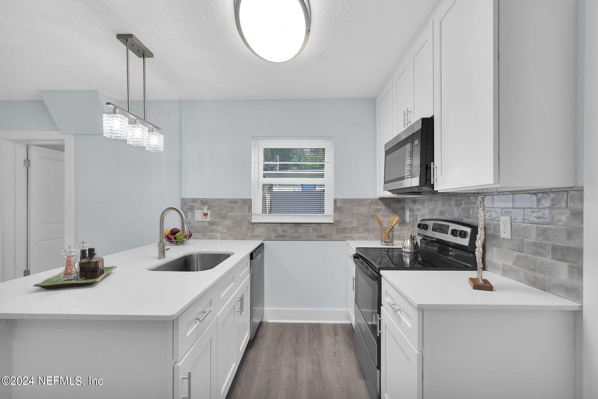6763 Ector Road Jacksonville, FL 32211 - Photo 16 of 28 a kitchen with a sink dishwasher a stove a microwave oven and a dining table with wooden floor