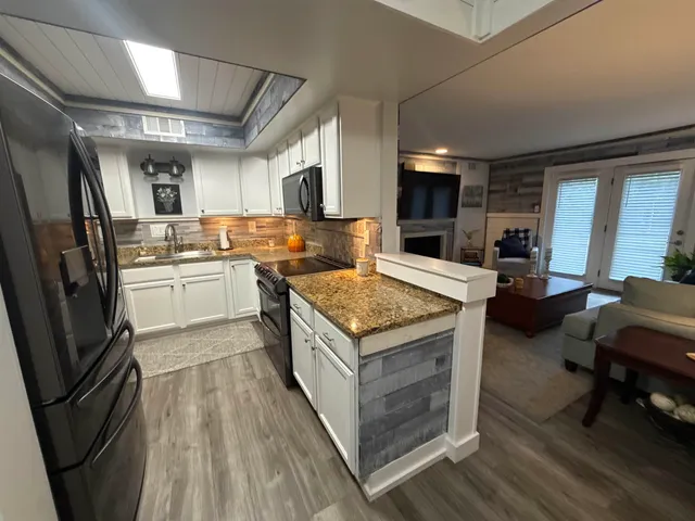 a kitchen with a stove a refrigerator and chairs