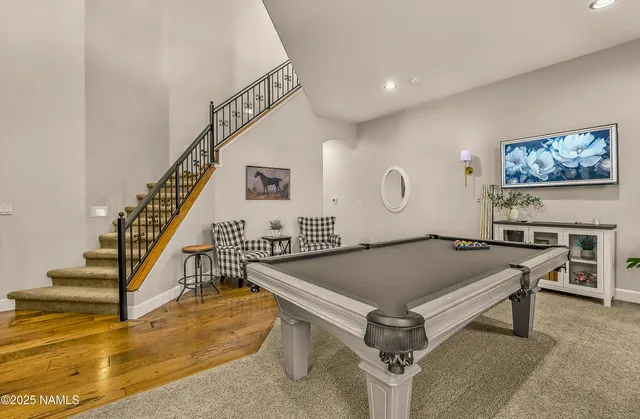 a living room with furniture pool table and windows