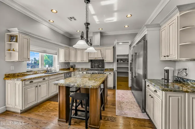 a kitchen with stainless steel appliances granite countertop a kitchen island a stove a refrigerator a oven and a sink with large countertops