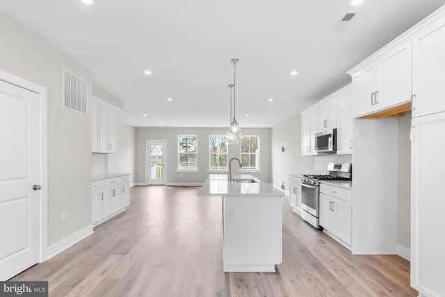 a open kitchen with white cabinets and stainless steel appliances