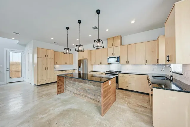 a large kitchen with stainless steel appliances granite countertop a stove a sink a oven and a refrigerator with white cabinets