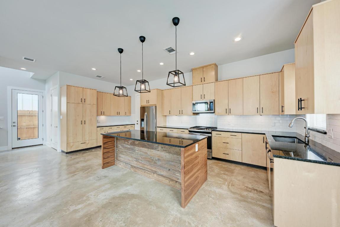 a large kitchen with stainless steel appliances granite countertop a stove a sink a oven and a refrigerator with white cabinets