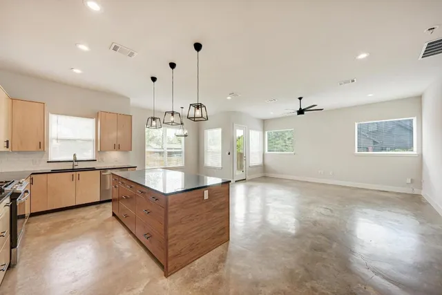 a large kitchen with stainless steel appliances kitchen island granite countertop a refrigerator and a sink