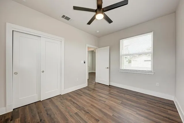 an empty room with wooden floor and ceiling fan