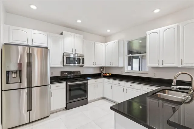 a kitchen with granite countertop a sink stainless steel appliances and cabinets