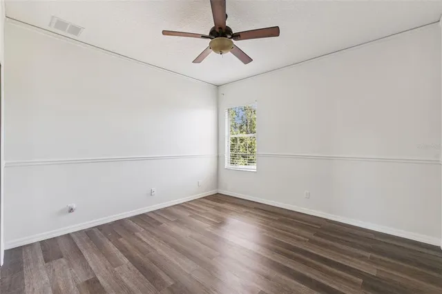 a view of a room with wooden floor and a ceiling fan