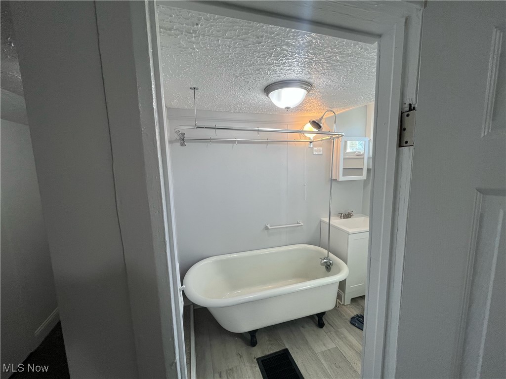 4278 Warner Road Cleveland, OH 44105 - Photo 20 of 44 Bathroom featuring a textured ceiling, a freestanding tub, vanity, and wood finished floors
